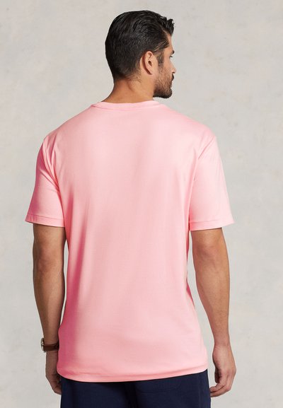 Jasnoróżowy t-shirt z krótkim rękawem, okrągłym dekoltem, gładką fakturą i luźnym krojem. Widok z tyłu ukazuje czysty i prosty design.