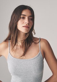 Szary prążkowany top na ramiączkach. Dopasowany krój i miękka tekstura z dekoltem w serek. Prosty i minimalistyczny styl.