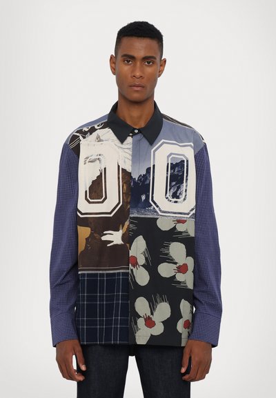 Collared, patchwork shirt featuring mixed patterns in blue, black, and white with floral and abstract designs, long sleeves, and button closure.
