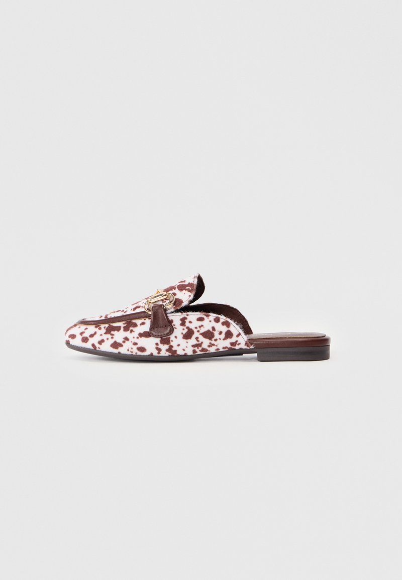 Chaussure en cuir à enfiler avec un motif tacheté marron et blanc, ornée d'une touche de matériel doré et d'une semelle plate.