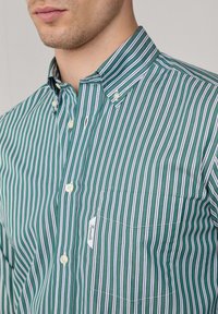 Groene en witte gestreepte katoenen shirt met een button-down kraag, voorzien van een borstzak en een label op de zak.
