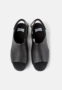Scarpe aperte in pelle nera con una finitura texturizzata, dotate di un design slingback e di una morbida soletta nera. Logo visibile sulla soletta.