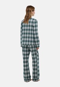Ensemble de pyjama à carreaux vert et blanc comprenant un haut à manches longues et un pantalon ample. Fabriqué en tissu doux avec un motif à carreaux.