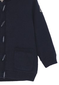 Cardigan lavorato a maglia di colore blu navy con parte anteriore a costine testurizzate, chiusura a bottoni e una tasca applicata sul davanti. Dotato di cappuccio.