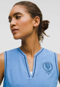 Top atletico senza maniche blu con scollatura a V e rifiniture blu navy, dotato di un logo del club di tennis con racchetta e dettaglio di corona. La texture appare liscia.