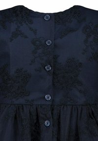Navyblaues Kleid aus strukturiertem Stoff, mit floralen Stickereien und fünf Knöpfen auf der Rückseite. Glockenrock mit gerafftem Detail.