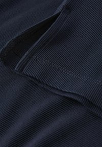 Tumši zilās ribot�ās audums, kas parāda struktūru un spīdumu, ar redzamām šuvēm. Materiāls ir mīksts un apvieno gludu virsmu ar rievotu rakstu.