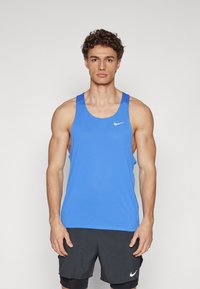 Blaues ärmelloses Nike-Trägershirt aus strukturierter Stoff; mit einem runden Ausschnitt und einem kleinen weißen Logo auf der Brust.