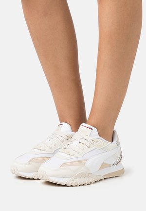 Zapatillas blancas con acentos en beige, materiales de malla texturizada y cuero, con cordones redondos, suelas acolchadas y una suela con patrón.