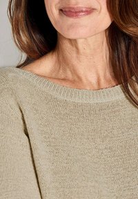 Beige gebreide trui met een wijde ronde hals, voorzien van een textuurpatroon. Zachte stof valt iets om de schouders.