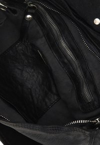Interno in pelle nera di una borsa, con più tasche con zip, una finitura testurizzata e fodera in tessuto liscio.