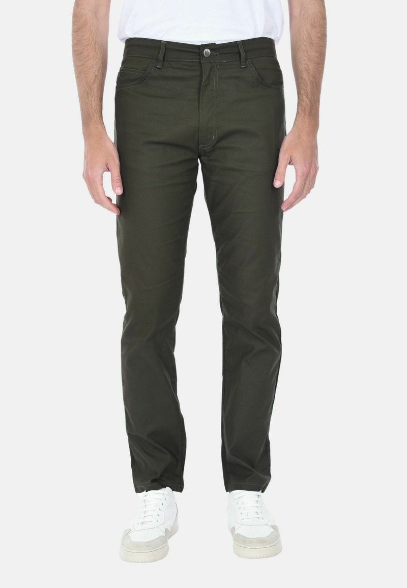 Pantaloni in misto cotone verde con vestibilità slim, dotati di tasche anteriori, chiusura con bottone e cuciture a contrasto, abbinati a sneaker bianche.