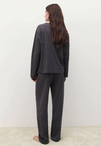 Šedý souprava domácího oblečení zahrnuje dlouhý rukáv s uvolněným střihem a odpovídající volné kalhoty, oboje vyrobené z měkké tkaniny.