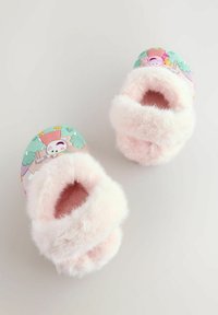 Flauschige rosa Hausschuhe mit einer weichen Felltextur. Der obere Teil zeigt ein farbenfrohes Cartoon-Motiv auf grünem Hintergrund. Offene Zehen.