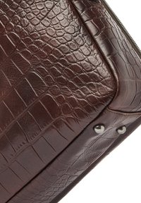 Bruine leren tas met krokodillenpatroon, voorzien van een gestructureerde afwerking en zilverkleurige metalen accenten op de onderste hoeken.