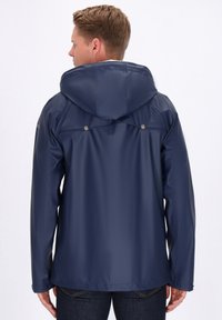 Jachetă impermeabilă de culoare albastru închis, cu glugă, având o textură netedă, capse pe spate și mâneci lungi.