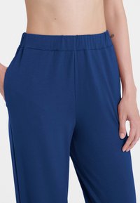 Pantaloni leggeri color blu navy con vita elasticizzata, caratterizzati da una texture liscia e una vestibilità comoda, mostrati in vita e sui fianchi.