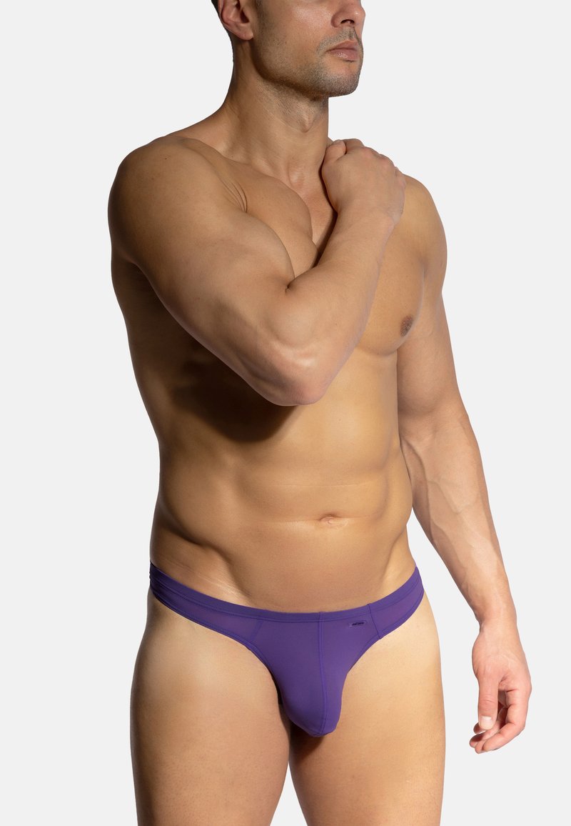 Lila Herren-Tanga, aus weichem Stoff gefertigt. Verfügt über eine glatte Textur, einen niedrigen Bund und ein Design mit minimaler Abdeckung.