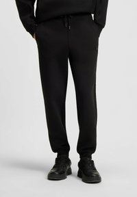 Schwarze Jogginghose aus weichem Stoff, mit geradem Bein, elastischem Bund mit Kordelzug und seitlichen Taschen.