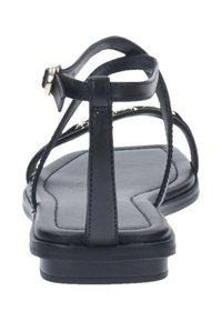 Sandalias negras con tiras finas y suela plana. El diseño incluye una tira central en forma de T y un pequeño detalle de hebilla ajustable.