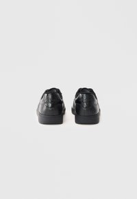 Mustad mustad mustad nahast �ülemise, tekstuurse kanna detaili, ümarate varvaste ja tasase kummist talla ning minimalistliku disainiga.
