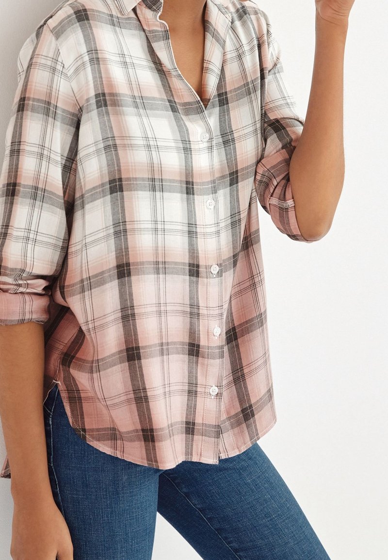 Lys rosa og gråternet skjorte med knapper og krave, lærredede ærmer og en let buet kant, lavet af blødt stof. Jeans synlige nedenfor.