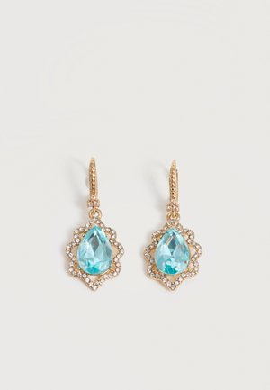 Χρυσά σκουλαρίκια με σταγόνα και μπλε πολύτιμους λίθους σε σχήμα σταγόνας, περιβάλλονται από μικρούς διαυγείς κρυστάλλους σε ανοιχτό φόντο.