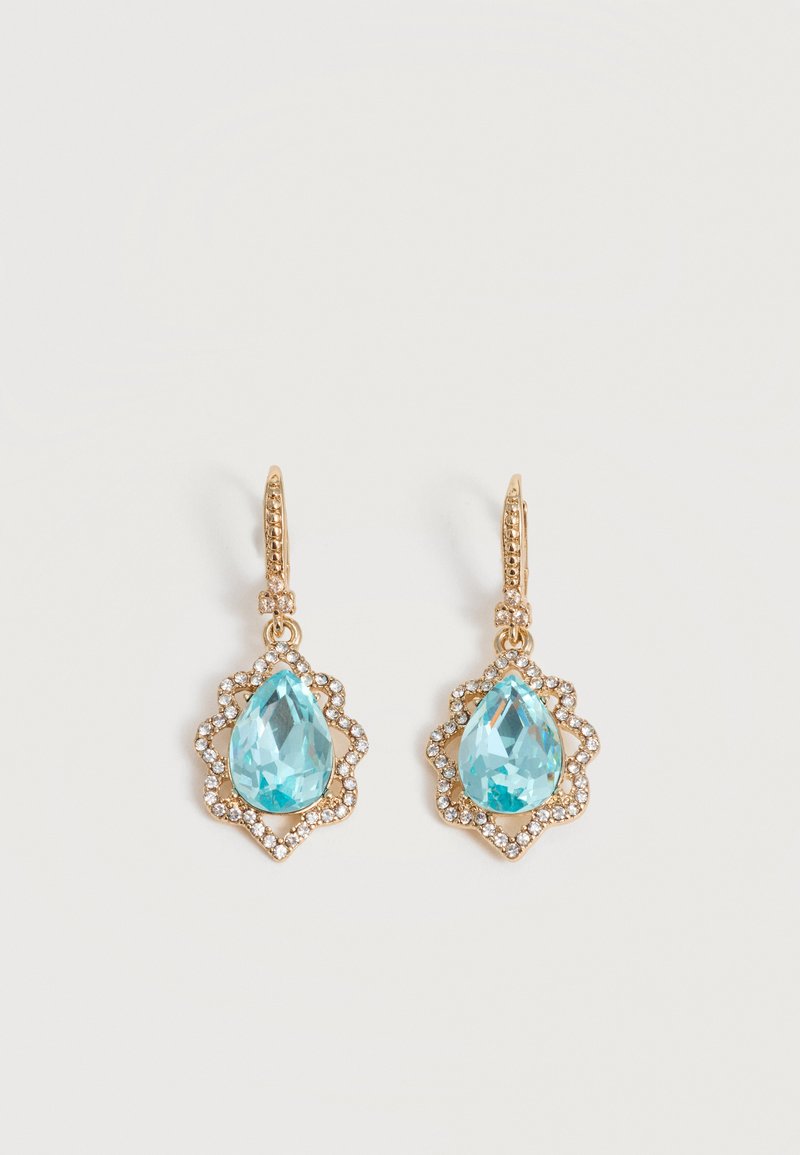 Χρυσά σκουλαρίκια με σταγόνα και μπλε πολύτιμους λίθους σε σχήμα σταγόνας, περιβάλλονται από μικρούς διαυγείς κρυστάλλους σε ανοιχτό φόντο.