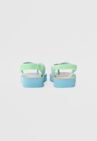 Flip-flops verzi cu o talpă albastră, având o branț cu model. Curelele sunt texturate, iar designul general este plat și casual.