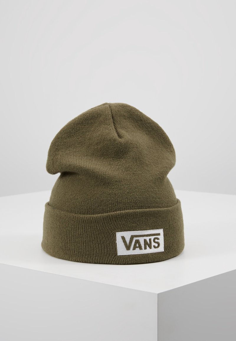 Bonnet tricoté vert olive avec revers, doté d'un patch logo Vans blanc rectangulaire, présenté sur un piédestal blanc.