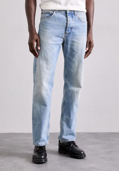 Jeans en denim bleu clair avec une coupe droite, lavage délavé et design à cinq poches. Portés avec des chaussures noires à lacets.