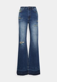 Calças de ganga flare em azul escuro, com remendos desgastados e costura decorativa. Material: algodão com detalhes de bainha desfiada.