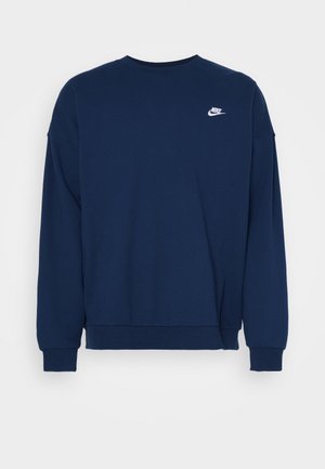 Tumesinine dressipluus pikkade varrukatega, ümmargune kaelus, soonikkoes mansetid ja alumine äär; rinnal on väike valge Nike logo.