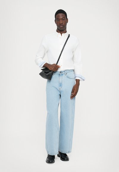 White long-sleeve shirt, light blue wide-leg jeans, black crossbody bag, and black shoes. Notable features: buttoned collar and rolled sleeves.