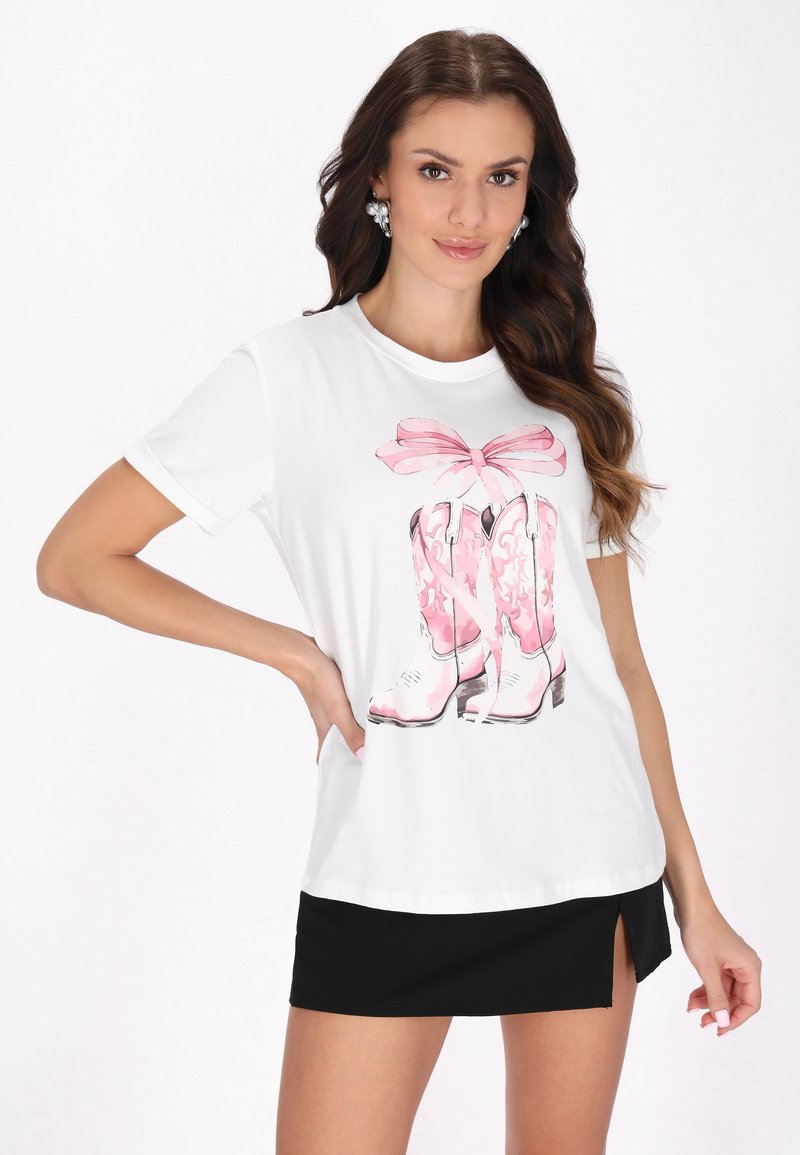 Hvid t-shirt med et pink cowboystøvle grafik med en sløjfe. Korte ærmer, afslappet pasform, parret med en sort miniskirt.