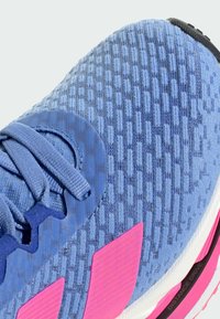 Blauwe sportieve schoen met een gestructureerde bovenkant, met een roze accent en een rond vetersysteem. Ontworpen voor comfort, met een gevoerde zool.