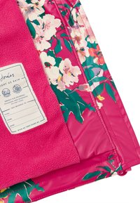 Giacca impermeabile rosa con motivo floreale e morbida fodera in fleece. Include un'etichetta per la personalizzazione. Accentuata da foglie verdi vivaci.