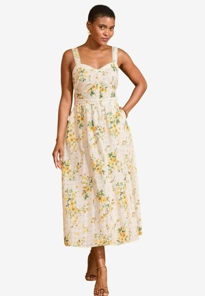 Kukallinen midi-mekko, jossa on beige perusta, keltaisia ja vihreitä kukkakuoseja, pitsiyksityiskohtia ja muotoiltu yläosa leveillä olkaimilla.