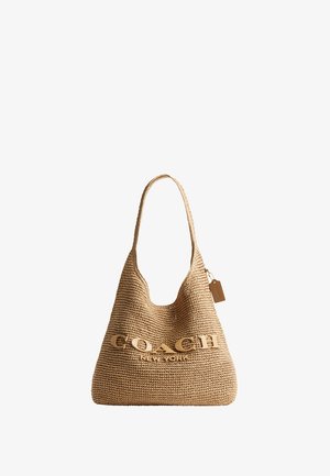 Geantă mare de paie împletită de culoare bronz cu o singură curea pe umăr și un logo mare "COACH NEW YORK" pe partea din față, precum și o etichetă mică atârnată pe lateral.