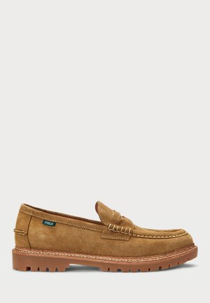 Mocassins en daim marron avec un design à bout moc, semelle en caoutchouc et couture décorative de selle. Présente une petite étiquette bleue "Polo" sur le côté.