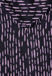 Il tessuto a V presenta uno sfondo scuro con strisce lavanda allungate, creando un motivo alternato. La tessitura testurizzata aggiunge profondità.