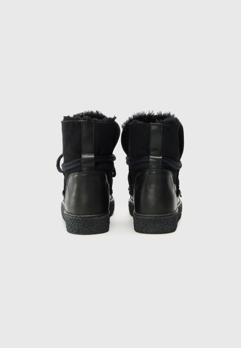 Czarne botki za kostkę z teksturowaną gumową podeszwą, zamszową cholewką i sztucznym futrem w środku. Posiadają sznurowanie i pętelkę z tyłu.