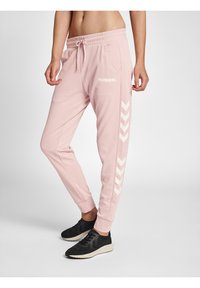 Rosa sweatpants med elastisk midja, med sidfickor och vita chevronränder längs sidan. Tillverkade av mjukt, strukturerat tyg.