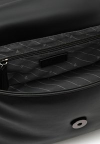 Bolso de mano de cuero negro con una textura suave, que cuenta con un interior forrado en gris, un bolsillo con cremallera y un cierre a presión metálico.