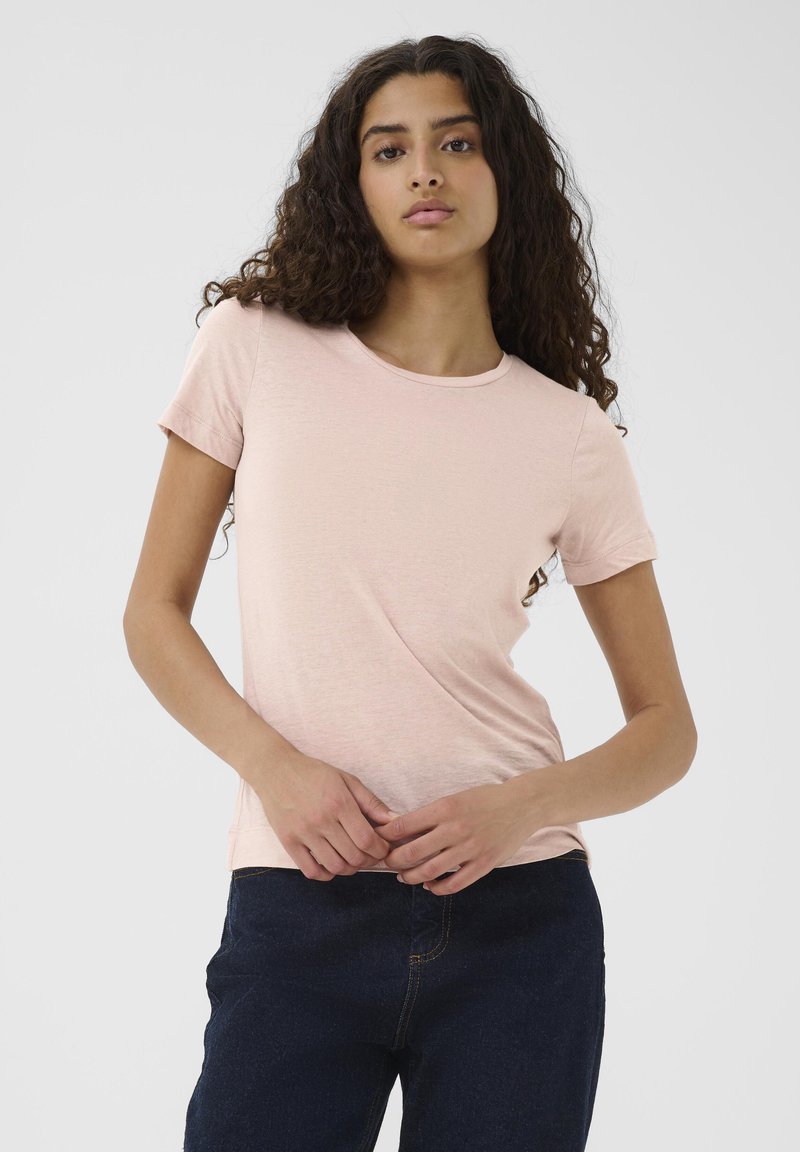 Helles rosa T-Shirt mit kurzen Ärmeln aus weichem Material, mit einem Rundhalsausschnitt und einem lockeren Schnitt, kombiniert mit dunkelblauen Jeans.