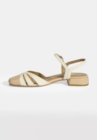 Beige en crème slingback schoenen met een vierkante neus, voorzien van kruislussen en een lage blokhak, gemaakt van glad leer.