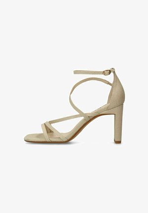 Sandale à talon haut beige avec des fines lanières croisées sur le pied et une bride à la cheville munie d'une petite boucle.