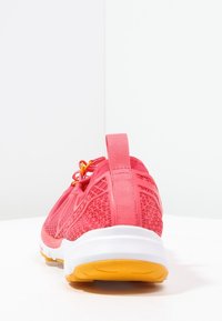 Rosa sportskor med meshmaterial och geometriska uttag, med gula snören, en texturerad hälflik och en vit mellansula med en gul yttersula.