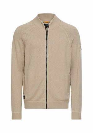 Beige cardigan med lynlås, ribstrikket krave og ærmekanter, med sort lynlås og diskret strikket tekstur. Simpelt design uden fremtrædende mønstre.