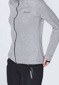 Szara polarowa kurtka z wysokim kołnierzem, przednim zamkiem błyskawicznym i czarnymi akcentami. Posiada subtelne logo i dopasowany krój.